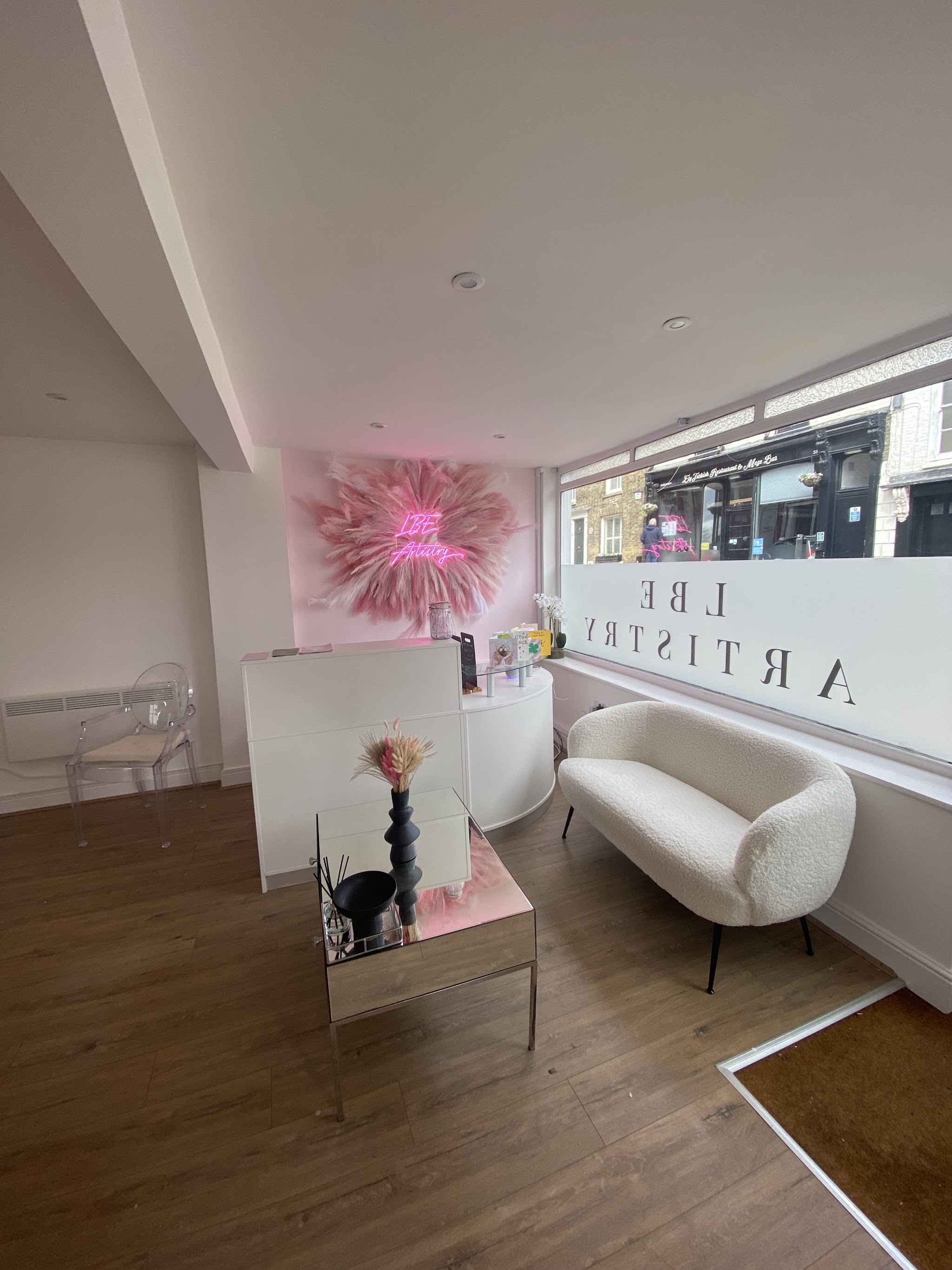 Reception with a white boucle sofa and the pink feather neon wall