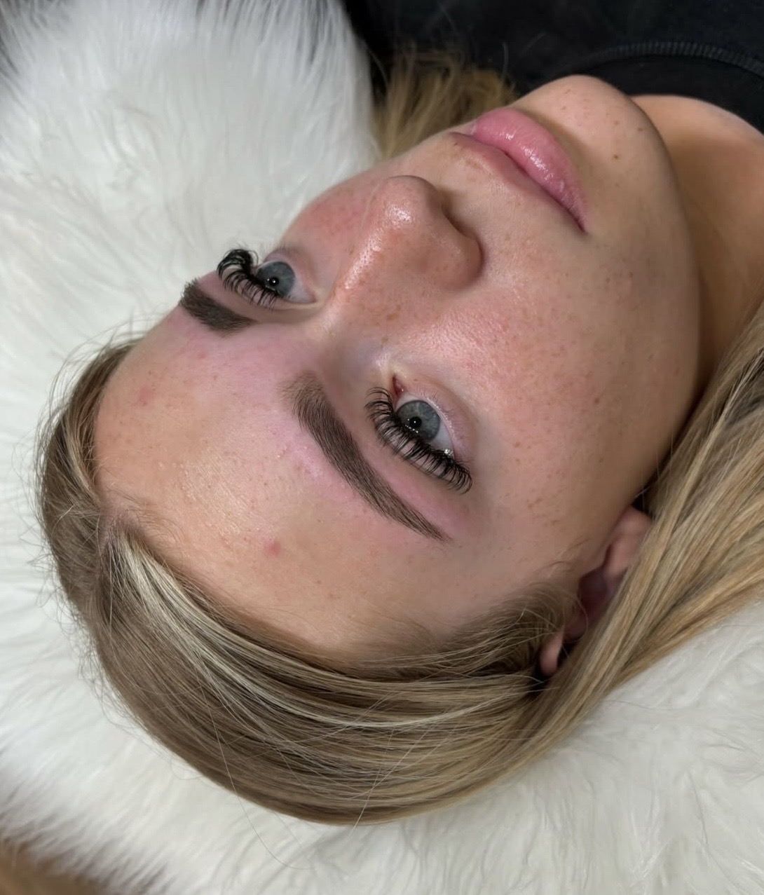 Lash extensions and brows on a client lying on white fur