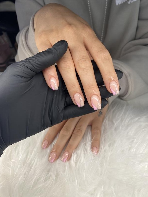 Soft pink BIAB nails held in a gloved hand